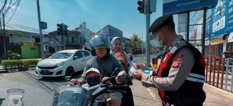 polisi bagikan masker kepada pengendara motor yang melintas